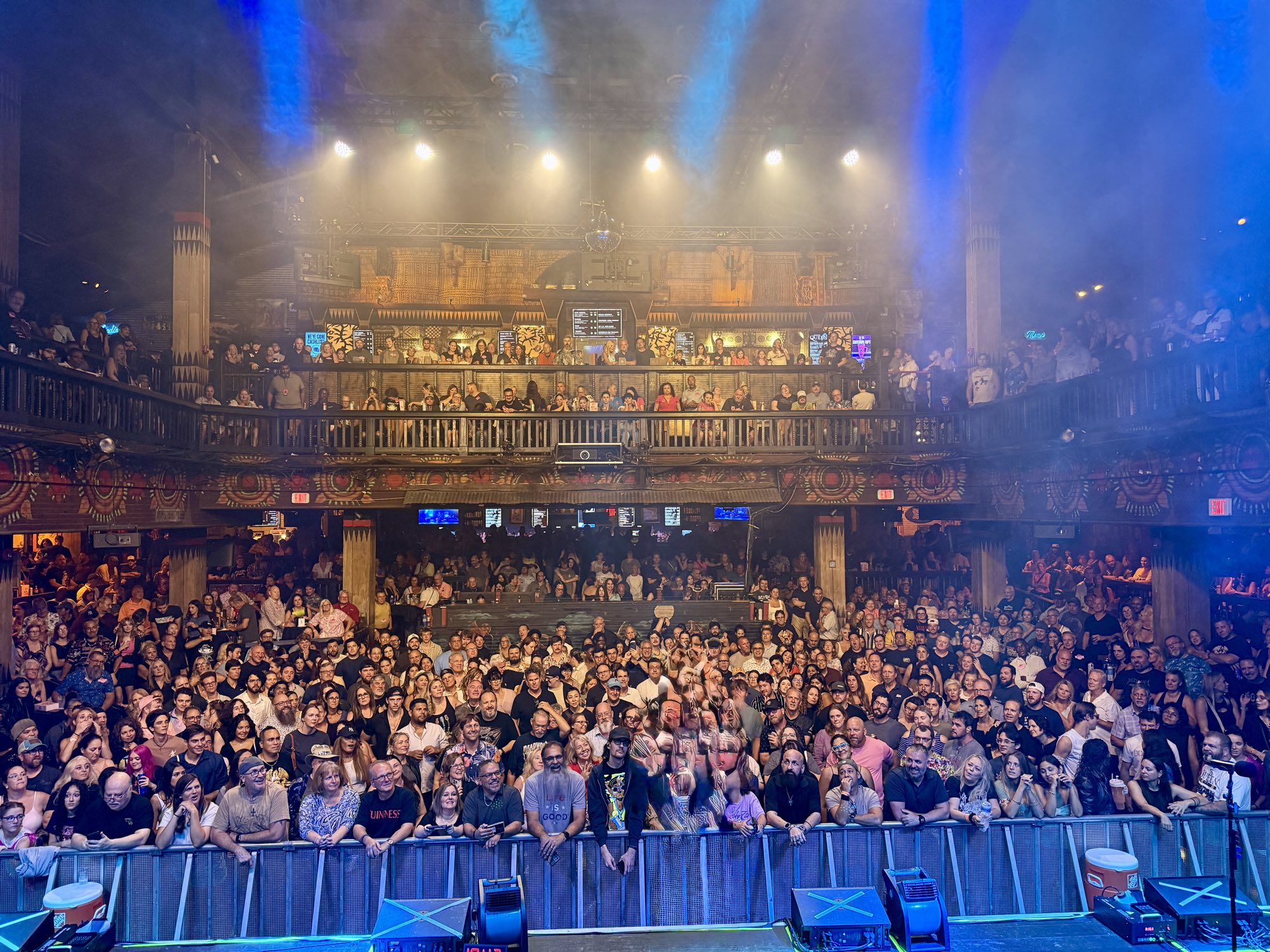 A packed house seen from an empty stage, lights up